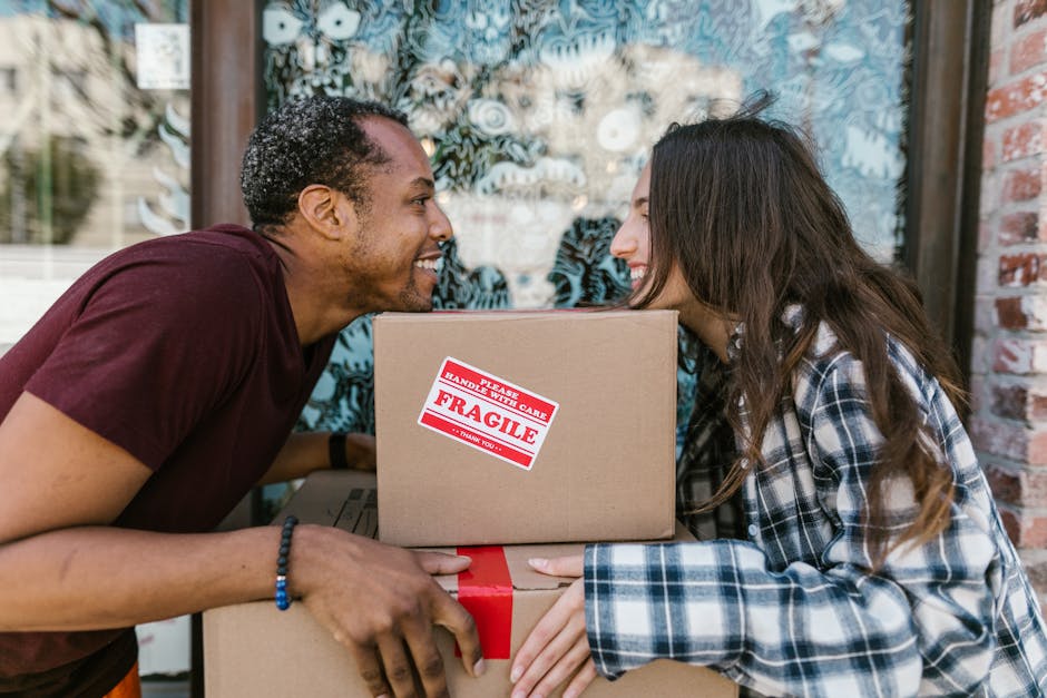 Close-up image of two light brown cardboard boxes used for home relocation, placed on a wooden floor inside a property. The upper box has the word 'STUFF' written in large red marker, accompanied by a